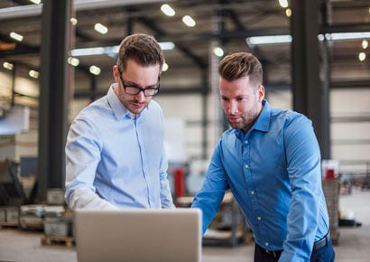 Two men using laptop and discussing