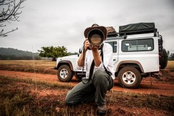 man with camera lens in front of a jeep in the wilderness