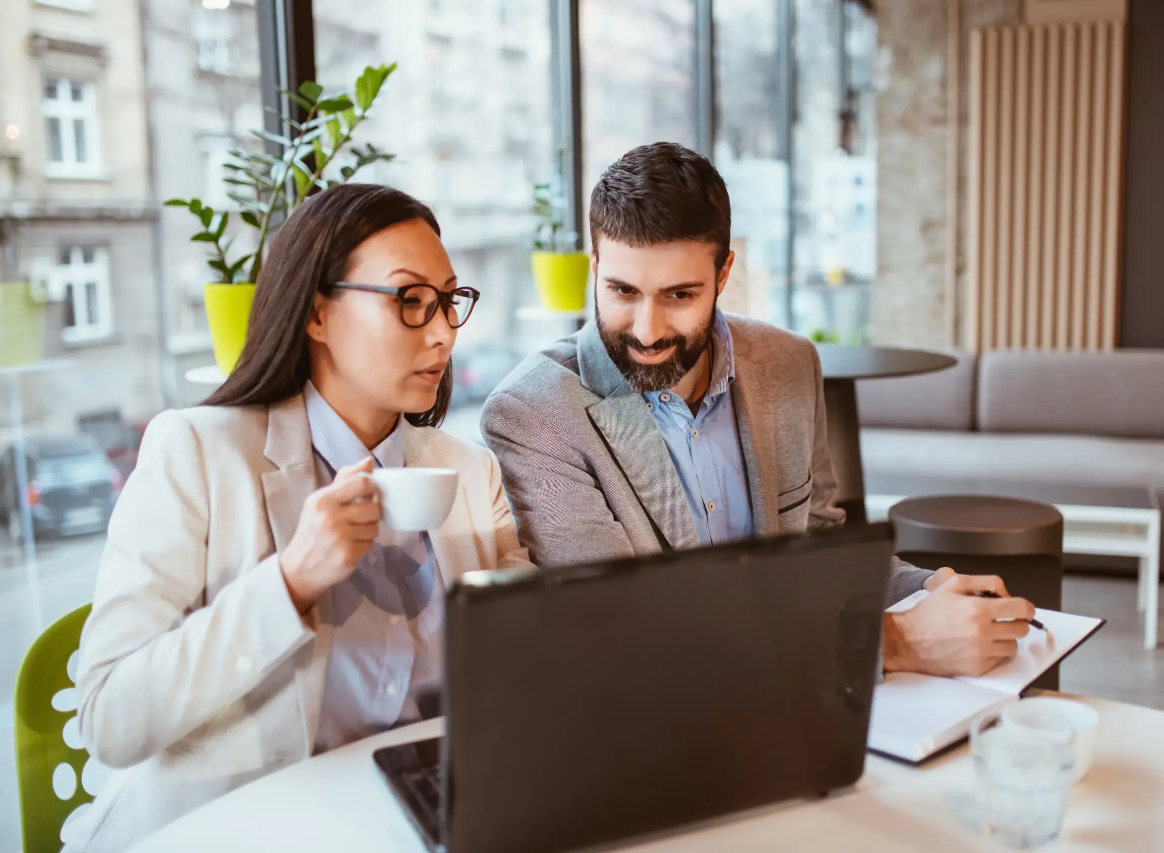 A lady holding a coffee mug and both looking at the laptop