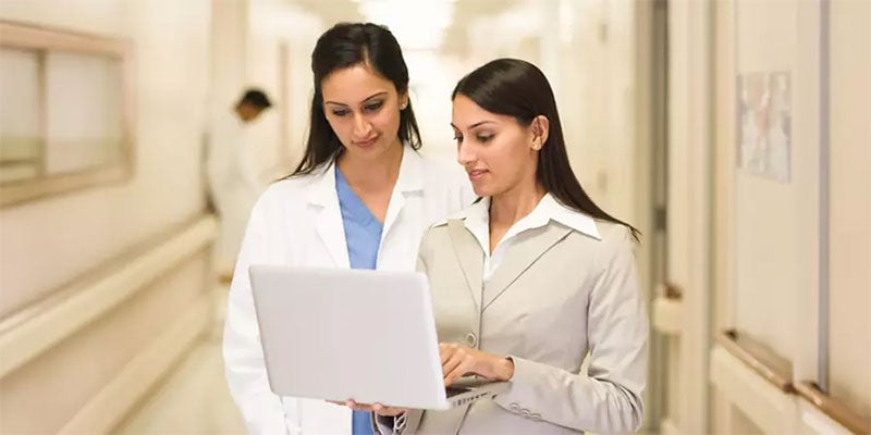 Two doctors see the report on their laptop.